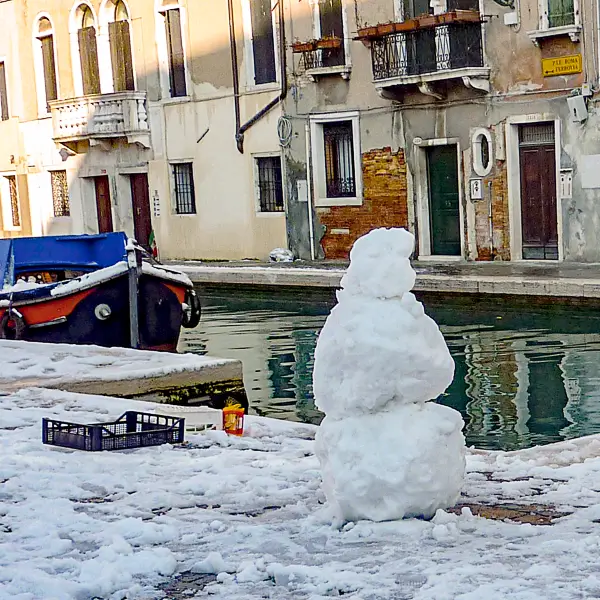 A snowman stands next to a canal during a rare March snowstorm in Venice.